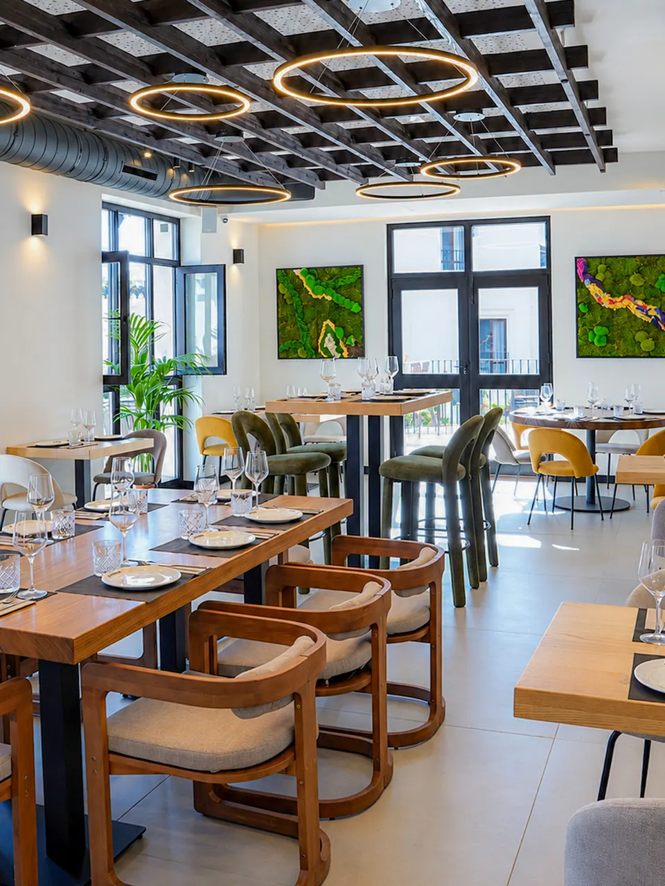 Interior de La Pilastra, con mesas de madera, vegetación y luz natural