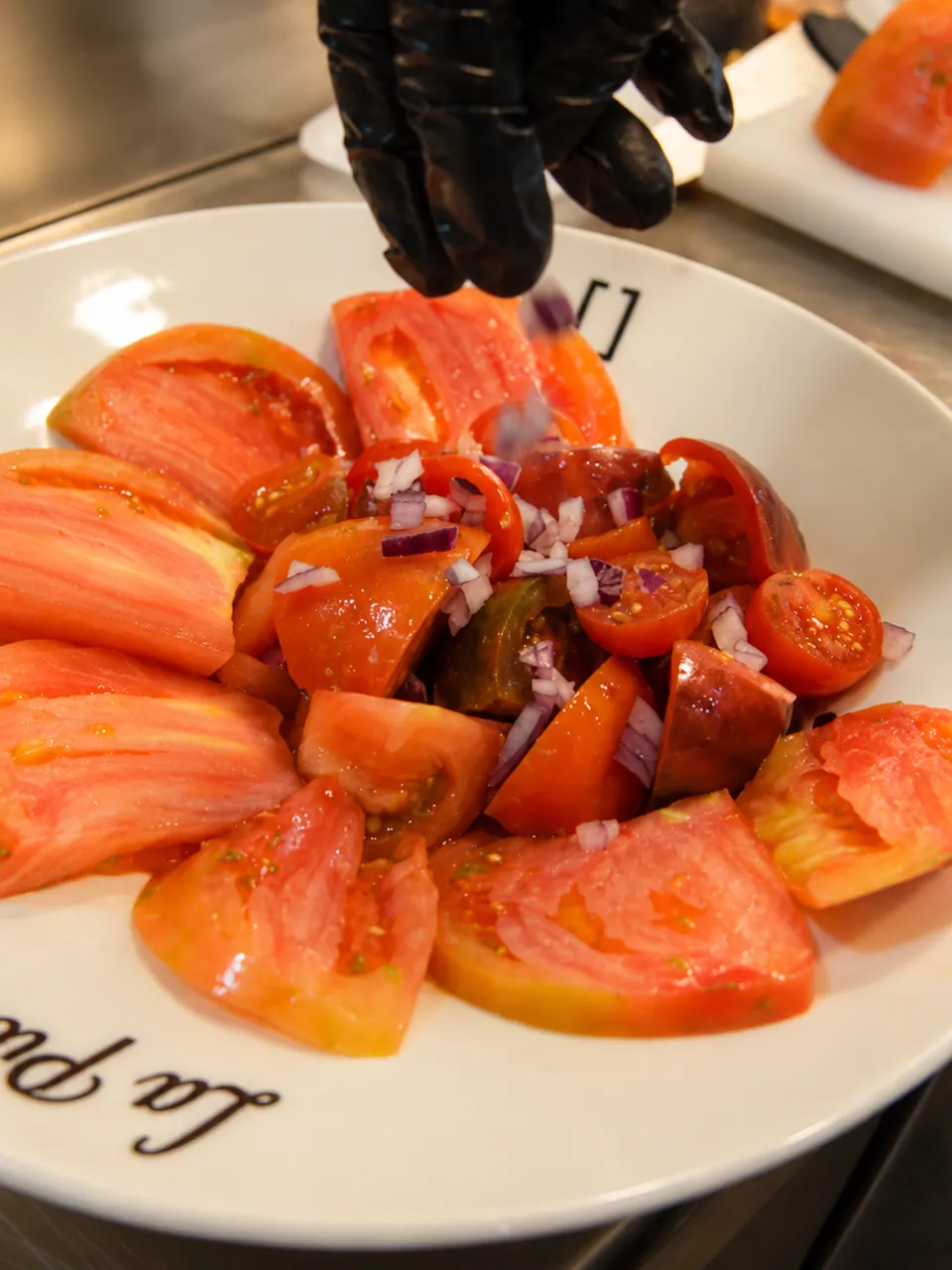 Variado de tomates con cebolla morada emplatado en la cocina de La Pilastra