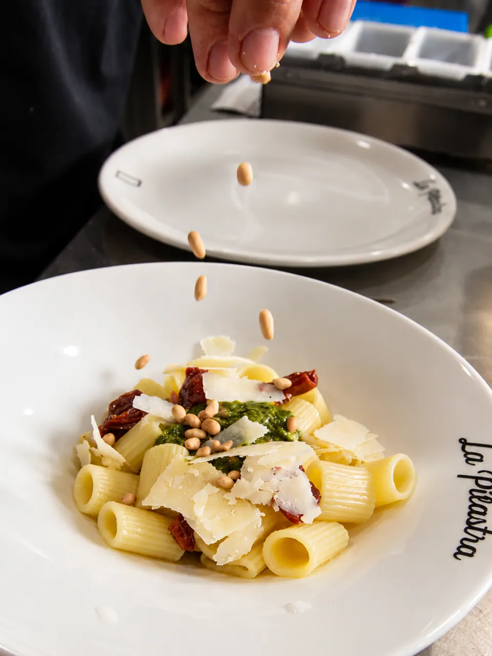 Pasta fresca al pesto terminada con piñones en La Pilastra